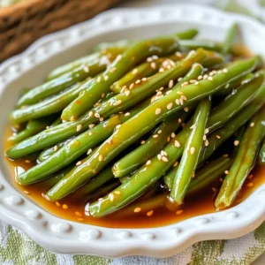 - 1 pound fresh green beans, trimmed - 3 tablespoons honey - 2 tablespoons soy sauce - 3 cloves garlic, minced - 2 tablespoons olive oil - 1 tablespoon sesame seeds - Salt and pepper to taste You can swap honey for maple syrup or agave nectar if needed. For a low-sodium option, try low-sodium soy sauce. If you don’t have fresh garlic, use garlic powder, but reduce the amount. When choosing fresh green beans, look for ones that are bright and firm. Avoid any that are limp or have brown spots. For soy sauce, brands like Kikkoman or San-J are great choices. Fresh garlic packs more flavor than jarred garlic, so opt for fresh whenever possible. {{ingredient_image_1}} To start, we need to blanch the green beans. Blanching means cooking them in boiling water for a short time. This helps keep their bright color and crisp texture. 1. Fill a large pot with water and add a good amount of salt. 2. Bring the water to a boil. 3. Add the trimmed green beans and let them cook for about 3 minutes. 4. You want them to be bright green and slightly tender. Next, we need an ice bath. An ice bath stops the cooking process. It keeps the beans crunchy. 1. Prepare a bowl with ice and cold water. 2. Once the beans are blanched, drain them. 3. Quickly transfer the beans to the ice bath. 4. Let them cool for a few minutes, then drain again. Now, let's whip up the honey garlic sauce. This sauce is the star of the dish. It brings sweet and savory flavors together. 1. In a small bowl, combine the honey, soy sauce, and minced garlic. 2. Add a pinch of black pepper for a little extra flavor. 3. Use a whisk to mix everything well until smooth. You can adjust the sauce to your taste. If you like it sweeter, add more honey. For a saltier kick, add a bit more soy sauce. Cooking the green beans and sauce together is where the magic happens. This step gives the beans a nice texture and flavor. 1. Heat olive oil in a large skillet over medium heat. 2. Add the blanched green beans to the skillet. 3. Sauté them for about 5 minutes, stirring often. You want them to crisp slightly. After sautéing, pour the honey garlic sauce over the green beans. Toss them to coat evenly. 1. Cook for an additional 2-3 minutes. 2. You’ll notice the sauce thickens and glazes the beans. Finally, sprinkle sesame seeds over the beans. Toss gently to mix. Cook for one more minute to toast the seeds slightly. Now, your honey garlic green beans are ready to enjoy! To boost flavor in honey garlic green beans, try adding a few extra spices. A pinch of red pepper flakes adds heat. A dash of ginger gives a fresh zing. You can also add black sesame seeds for a nutty touch. Fresh herbs can brighten the dish. Chopped cilantro or basil works well. They add a lovely aroma and color. Try adding them right before serving for the best flavor. You can cook these green beans in different ways. Roasting them in the oven gives a nice crisp. Toss them in olive oil and seasonings before roasting. This method brings out their natural sweetness. Grilling is another fun option. It adds a smoky flavor that pairs well with honey. Just be sure to watch the cooking time. Aim for a tender but firm texture. Honey garlic green beans pair well with many main dishes. They complement grilled chicken or salmon perfectly. Serve them alongside rice for a great meal. For a pretty presentation, use a large serving platter. Drizzle any leftover sauce over the beans. Garnish with sesame seeds and chopped green onions for a pop of color. Pro Tips Blanching for Bright Color: Blanching the green beans in salted water helps maintain their vibrant color and crisp texture, making for an appealing dish. Honey for Sweetness: Adjust the amount of honey according to your taste preference. You can also use maple syrup for a different flavor profile. Garlic Flavor Boost: For a stronger garlic flavor, you can sauté the minced garlic in the olive oil before adding the green beans. Serving Suggestions: Serve the honey garlic green beans over rice or quinoa for a light, healthy main course or as a vibrant side dish. {{image_2}} You can mix it up with different veggies. Try asparagus or broccoli instead of green beans. Each choice brings a new taste and texture. Just remember to blanch them the same way. If you want protein, add chicken or tofu. Cook chicken pieces until golden, then toss them in with the beans. For tofu, use firm tofu and sauté it until crispy before mixing it in. Want to spice things up? Add red pepper flakes for heat. A little goes a long way. You can also add fresh ginger for a zingy twist. You can switch between sweet and savory flavors too. If you prefer less sweetness, cut back on honey. For extra sweetness, add a touch more honey or even some brown sugar. Need a gluten-free dish? Use gluten-free soy sauce instead of regular. It tastes just as good and keeps the dish safe for those avoiding gluten. If you want a vegan option, skip the honey. Use maple syrup or agave nectar instead. Both will give you that sweet flavor without animal products. To store leftovers, let the honey garlic green beans cool completely. Place them in an airtight container. This keeps them fresh for up to three days. You can use glass or plastic containers. Both work well and help lock in flavor. The best way to reheat is on the stove. Heat a skillet over medium heat. Add a splash of water or a bit of olive oil. This helps keep the green beans crisp. Stir gently until heated through, about 3-5 minutes. Avoid the microwave if you can. It may make the beans soggy. Yes, you can freeze honey garlic green beans. However, they taste best fresh. To freeze, cool the beans completely. Place them in a freezer-safe bag or container. Remove as much air as possible. When ready to eat, thaw in the fridge overnight. Reheat in a skillet for the best texture. To blanch green beans, follow these steps: 1. Boil Water: Fill a large pot with water and add salt. Bring it to a rolling boil. 2. Add Beans: Carefully add the trimmed green beans to the boiling water. 3. Cook: Boil for about 3 minutes. The beans should turn bright green and be slightly tender. 4. Ice Bath: Quickly drain the beans and transfer them into a bowl of ice water. This stops cooking and keeps the beans crunchy. 5. Drain Again: After a few minutes, drain the beans from the ice bath. Your beans are now ready for cooking! Yes, you can make honey garlic green beans ahead of time. Here are tips for storage and reheating: - Storage: Keep the green beans in an airtight container in the fridge. They stay fresh for about 3 days. - Reheating: To reheat, warm them in a skillet over low heat. Add a splash of water to keep them moist. Stir gently until heated through. To thicken your honey garlic sauce, try these methods: - Simmer Longer: Cook the sauce longer on medium heat, allowing it to reduce. It becomes thicker as it simmers. - Cornstarch Slurry: Mix 1 tablespoon of cornstarch with 1 tablespoon of cold water. Stir this mixture into the sauce and cook for a minute until thickened. Yes, you can use frozen green beans, but here are some tips: - Thaw First: Thaw the beans in the fridge overnight or use the microwave. - Blanching: You may skip the blanching step since frozen beans are often pre-blanched. Just sauté them directly. - Cooking Time: Frozen beans may need a bit longer to cook than fresh ones, so watch for doneness. Honey garlic green beans provide several health benefits: - Vitamins: They are rich in vitamins A, C, and K. - Fiber: Green beans offer dietary fiber that aids digestion. - Low Calorie: This dish is low in calories and fat, making it a healthy side. Enjoy the taste and health benefits of this simple yet flavorful side! In this blog post, we explored how to make delicious honey garlic green beans. We covered essential ingredients, alternative options, and tips for selecting quality items. You learned the step-by-step process to prepare and cook, plus suggestions for enhancing flavor and serving. As you create this dish, remember to experiment with your favorite vegetables and proteins. With a few simple tweaks, you can make this recipe your own. Enjoy the cooking process and the tasty results!