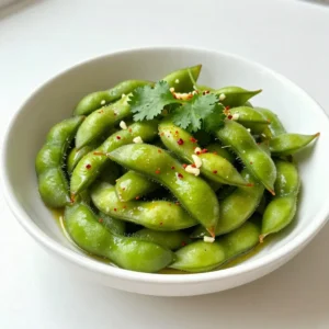 - 2 cups edamame (in pods) - 2 tablespoons olive oil - 4 cloves garlic, minced - 1 teaspoon red pepper flakes - 1 tablespoon soy sauce - 1 tablespoon sesame oil - 1 teaspoon honey or maple syrup - Sea salt, to taste - Fresh cilantro, for garnish I love using fresh ingredients for my Spicy Garlic Edamame. Edamame is young soybeans. They are tasty and full of protein. You can find them in pods at most grocery stores. First, you need 2 cups of edamame. Make sure they are fresh and firm. Next, I use olive oil to cook the garlic. It adds a nice flavor. You will need 2 tablespoons for this. Garlic is a must in this dish. You will need 4 cloves, minced. This gives the edamame a great taste. If you like spice, add 1 teaspoon of red pepper flakes. You can adjust this based on your taste. For flavor, you’ll need 1 tablespoon of soy sauce and 1 tablespoon of sesame oil. These sauces mix well with the edamame. A hint of sweetness comes from 1 teaspoon of honey or maple syrup. Finally, you will sprinkle sea salt to taste. Fresh cilantro makes a lovely garnish. It adds color and flavor too. Gather all these ingredients and get ready to make a delicious snack! {{ingredient_image_1}} - First, prepare a large pot of salted water. - Bring it to a boil. - Add 2 cups of edamame to the pot. - Cook the edamame for about 5 minutes. - Check if they are tender but still firm. - After cooking, drain the edamame in a colander. - Prepare a bowl filled with ice water. - Transfer the edamame to the ice water. - Let them sit for 2-3 minutes. - Drain again and set aside. - In a large skillet, heat 2 tablespoons of olive oil. - Use medium heat for a better sauté. - Add 4 cloves of minced garlic to the skillet. - Sauté for about 1 minute until fragrant. - Do not let the garlic brown. - Sprinkle in 1 teaspoon of red pepper flakes. - Stir for another 30 seconds to infuse the oil. - Add the drained edamame to the skillet. - Toss in 1 tablespoon of soy sauce. - Add 1 tablespoon of sesame oil and 1 teaspoon of honey. - Stir-fry for 2-3 minutes. - This helps the edamame get heated and coated well. - Remove from heat, sprinkle with sea salt, and garnish with fresh cilantro. To cook edamame just right, boil it for about 5 minutes. You want it tender but still firm. Overcooking can lead to mushy pods. After boiling, use an ice bath. This stops the cooking process quickly. Place the edamame in a bowl of ice water for 2 to 3 minutes. Then, drain it again. This method keeps your edamame vibrant and crisp. For spice lovers, red pepper flakes work wonders. Start with 1 teaspoon but adjust to your taste. If you like it spicier, add more! When seasoning with salt, sprinkle it lightly. You can always add more later, but it’s hard to take it away. Taste as you go to find your perfect balance. Spicy garlic edamame pairs well with drinks like beer or sake. It also makes a great party snack. For presentation, serve in a bowl. Garnish with fresh cilantro for a pop of color. A lemon wedge on the side adds a nice touch too, giving guests a chance to squeeze some fresh juice. Pro Tips Use Fresh Edamame: Fresh edamame has a better texture and flavor compared to frozen. If available, opt for fresh pods for the best taste. Adjust Spice Level: Feel free to modify the amount of red pepper flakes according to your spice tolerance. Start with less if you're unsure, and add more as needed. Garnish with Lemon: A squeeze of fresh lemon juice before serving can brighten the flavors and add a refreshing twist to the dish. Serving Suggestions: These spicy garlic edamame make a great appetizer or snack. Pair them with drinks or serve alongside sushi for a delightful meal. {{image_2}} You can spice up your edamame by adding more flavors. Try adding ginger for a fresh kick. You could also toss in bell peppers or green onions for extra crunch. If you want protein, consider adding cooked chicken, shrimp, or tofu for a heartier meal. You can steam edamame instead of boiling it. Just place the pods in a steamer basket over boiling water. Steam them for about 5 to 7 minutes until they are tender. Another method is oven-roasting. Preheat your oven to 400°F (200°C), toss the edamame with olive oil, and roast for about 15 minutes. This gives them a nice crispy texture. Get creative with your sauce! Instead of soy sauce, try teriyaki sauce for a sweet twist. You can also use chili oil to add even more spice. If you want a different sweetness, replace honey with maple syrup or agave nectar. Adjust these sauces to match your taste. To store your spicy garlic edamame, follow these steps: - Let the edamame cool down to room temperature. - Place it in an airtight container. - Store in the fridge for up to three days. When reheating, use a skillet over low heat. Add a splash of water to keep it moist. Stir often for even heating. You can also microwave it in short bursts. Just cover it with a damp paper towel. This helps to avoid drying out. Freezing is a great way to save leftover edamame. Here’s how: - First, let the cooked edamame cool completely. - Spread them on a baking sheet in a single layer. - Freeze for about an hour until firm. - Then, transfer them to a freezer bag. For thawing, simply place the bag in the fridge overnight. If you're in a hurry, you can use the microwave. Heat in short intervals until soft. Enjoy your edamame later as a quick snack! Edamame are young soybeans. They grow in pods and offer great nutrition. Each serving of edamame has about 120 calories, 11 grams of protein, and 8 grams of fiber. They are low in fat and rich in vitamins and minerals. Eating edamame has many health perks. They can help with weight loss due to their high fiber content. They also support heart health and may lower cholesterol levels. Edamame is a good source of antioxidants, which protect your body from damage. Overall, they are a tasty, healthy choice. Yes, you can prep this dish in advance. Cook the edamame and make the sauce, but don't combine them until you're ready to serve. This keeps the edamame fresh and crunchy. To store, place the cooked edamame in an airtight container. Keep it in the fridge for up to three days. You can also store the sauce separately in a jar. When you are ready, just heat the edamame and mix in the sauce for a quick snack. Yes, this recipe is vegan-friendly. The main ingredients—edamame, olive oil, garlic, and spices—are all plant-based. If you want to make it sweeter, you can use maple syrup instead of honey. This keeps the recipe vegan. Enjoy this dish without worry, knowing it fits your dietary needs! This blog post covered how to make a tasty spicy garlic edamame dish. You learned about the key ingredients, step-by-step cooking methods, and helpful tips for perfect texture and flavor. I shared variations, storage tips, and answered common questions. Enjoy making this healthy snack or side dish. You can customize it to your taste. Try different spices and cooking methods to find your favorite. Happy cooking!