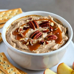- 8 oz cream cheese, softened - 1 cup powdered sugar - 1 cup whipped topping (like Cool Whip) - 1/2 cup pecans, finely chopped - 1/2 cup caramel sauce (plus extra for drizzling) - 1 tsp vanilla extract - Sea salt, for garnish - Graham crackers or apple slices, for dipping - Chopped chocolate or chocolate chips for extra sweetness - A sprinkle of cinnamon for warmth - Additional nuts like walnuts or almonds for crunch - Use Greek yogurt instead of cream cheese for a lighter dip. - Swap powdered sugar with honey or maple syrup for a natural sweetener. - If you lack pecans, any nut like almonds or hazelnuts works well. - For a dairy-free option, use vegan cream cheese and whipped topping. This rich and creamy dip is so easy to make and perfect for sharing. You can mix and match flavors by adding or changing some of the ingredients. Enjoy making this delightful treat with friends and family! {{ingredient_image_1}} Making caramel pecan cheesecake dip is quick and easy. You can make it in just 15 minutes. Gather all your ingredients before you start. This way, you won’t miss anything. You will need a mixing bowl and a spatula for mixing. A serving dish will also be handy. 1. In a mixing bowl, beat 8 oz of softened cream cheese with 1 cup of powdered sugar. Mix until the texture is smooth and fluffy. 2. Add 1 tsp of vanilla extract to your cream cheese mixture. Stir until everything blends well. 3. Gently fold in 1 cup of whipped topping. This keeps the dip light. Be careful not to overmix. 4. Next, add 1/2 cup of finely chopped pecans and 1/2 cup of caramel sauce. Fold these in gently to keep the fluffiness. 5. Transfer your dip to a serving dish. Drizzle extra caramel sauce on top for a sweet touch. 6. Finally, sprinkle a small pinch of sea salt over the caramel drizzle. This adds a nice contrast in flavor. 7. Serve your dip chilled with graham crackers or apple slices for dipping. To get the dip just right, remember these tips: - Use softened cream cheese. This helps it blend smoothly. - Fold in the whipped topping gently. This keeps it airy. - Don’t rush when mixing in the pecans and caramel. Take your time to keep the dip fluffy. - Serve it cold. Chilling helps the flavors blend well, making each bite delicious. To make the best caramel pecan cheesecake dip, start with room-temperature cream cheese. Softened cheese blends well, creating a smooth base. Beat the cream cheese and powdered sugar until fluffy. This step gives the dip its light texture. When adding whipped topping, fold it in gently. This keeps the dip airy and creamy. Chop your pecans finely for even distribution. They add crunch and flavor without overwhelming each bite. Use high-quality caramel sauce for a richer taste. If you want a fun twist, try making your own caramel sauce. Presentation makes your dip look as good as it tastes. Use a clear bowl to show off the layers. Drizzle extra caramel over the top before serving. It adds a sweet touch and makes it eye-catching. Sprinkle a pinch of sea salt on top for contrast. The salt enhances the sweetness and gives a gourmet feel. Serve the dip with graham crackers or apple slices arranged nicely around it. This not only looks great but also makes it easy for guests to dip. To elevate your dip, consider adding flavors. A splash of maple syrup can deepen the sweetness. You can also mix in a pinch of cinnamon for warmth. If you love chocolate, add mini chocolate chips for extra richness. For a seasonal twist, try incorporating pumpkin spice in the fall. It gives a fun autumn vibe to your dip. Finally, always taste as you go. Adjust the sweetness or salt to fit your preference. This way, you create a dip that’s perfect for you and your guests. Pro Tips Room Temperature Cream Cheese: Ensure your cream cheese is fully softened to room temperature for a smoother, creamier dip. Use Quality Caramel Sauce: Opt for a high-quality caramel sauce for the best flavor; homemade caramel can elevate your dip even further. Chill Before Serving: For the best texture, refrigerate the dip for at least an hour before serving to allow the flavors to meld. Mix-ins Variations: Feel free to experiment with other nuts or add chocolate chips for a different twist on this delicious dip. {{image_2}} You can mix things up with your Caramel Pecan Cheesecake Dip. Try adding chocolate for a rich twist. Just fold in 1/4 cup of cocoa powder or melted chocolate. You can also add fresh fruit. Chopped strawberries or blueberries brighten the dip. They add a fresh taste and color. Making this dip gluten-free is easy. Use gluten-free graham crackers for dipping. You can also slice fresh apples or pears. Both are tasty and safe for those with gluten issues. For the dip, check your powdered sugar. Some brands add gluten. Choose a gluten-free brand to stay safe. Graham crackers are great, but you have options. Pretzels add a salty crunch. You can use cookies for a sweet dipper. Vanilla wafers or biscotti work well too. For a fresh twist, try carrot sticks or celery. These add a nice crunch and a healthy touch. Experiment with what you like best! To keep your Caramel Pecan Cheesecake Dip fresh, place it in an airtight container. Make sure to cover it tightly. This step helps prevent air from drying it out. You can also use plastic wrap to cover the dip directly. Store the container in your fridge. When stored correctly, this cheesecake dip lasts about 3 to 5 days in the fridge. After that, it may lose its creamy texture and flavor. Always check for any off smells or changes in texture before eating leftovers. If it looks or smells funny, don’t take a chance. You don’t need to reheat this dip. It is meant to be enjoyed cold. If the dip seems a bit thick after storage, stir in a bit of milk or cream. This will help restore some creaminess. If you want to elevate the flavor, add a touch of fresh caramel sauce on top before serving. This gives it a nice boost! You can serve this dip with many tasty options. Graham crackers work great. They add a nice crunch. Apple slices provide a sweet and fresh taste. You can also try pretzels for a salty contrast. Want a fun twist? Use vanilla wafers or cookies. Each option pairs well with the creamy dip. Yes! You can make this dip a day ahead. Just cover it and store it in the fridge. This helps the flavors blend well. When you’re ready to serve, add a drizzle of caramel on top. This keeps the dip fresh and tasty. To keep your dip thick, avoid over-mixing the whipped topping. Fold it in gently. Too much mixing can add air and cause it to thin. Store it in an airtight container to keep moisture out. If you notice it getting watery, just stir it gently before serving. In this blog post, we covered the key ingredients, preparation steps, and tips for making a great cheesecake dip. We explored flavor variations and storage advice. Remember, achieving the right texture is vital for success. With these steps, you can impress anyone at your next gathering. Use the tips to enhance flavors and present your dip nicely. Make this dip your own and enjoy every bite. Now get in the kitchen and start creating!