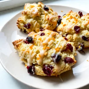 To make cranberry orange scones, gather these items: - 2 cups all-purpose flour - 1/3 cup granulated sugar - 1 tablespoon baking powder - 1/2 teaspoon salt - 1/2 cup unsalted butter, cold and cubed - 1/2 cup dried cranberries - Zest of 1 orange - 1/2 cup heavy cream - 1 large egg - 1 teaspoon vanilla extract Not all homes have every ingredient. You can swap some of these: - Use whole wheat flour instead of all-purpose flour for a heartier scone. - Coconut sugar or brown sugar can replace granulated sugar for a deeper flavor. - If you don’t have heavy cream, use milk or a non-dairy milk. Just keep the dough a bit thicker. - You can substitute the egg with a flax egg if you're vegan. Just mix 1 tablespoon of ground flaxseed with 3 tablespoons of water. Choosing the best ingredients makes a big difference. Here are my tips: - Look for flour that is fresh and finely ground. Check the date on the bag. - Choose unsalted butter to control the saltiness in your scones. Cold butter helps create a flaky texture. - When selecting cranberries, look for ones that are plump and not hard. This means they are fresher. - Use a bright, fragrant orange to get the best zest. The zest adds great flavor. With these ingredients and tips, your cranberry orange scones will shine! {{ingredient_image_1}} Start by preheating your oven to 400°F (200°C). This step is key for even baking. While the oven warms, line a baking sheet with parchment paper. This will keep the scones from sticking. In a large mixing bowl, whisk together 2 cups of all-purpose flour, 1/3 cup of granulated sugar, 1 tablespoon of baking powder, and 1/2 teaspoon of salt. Mixing these dry ingredients well is important for the scones’ structure. Make sure there are no clumps. Next, add 1/2 cup of cold, cubed unsalted butter to the flour mixture. Use a pastry cutter or your fingers to mix it in until it looks like coarse crumbs. Add in 1/2 cup of dried cranberries and the zest of 1 orange. Stir until everything is mixed evenly. In another bowl, whisk together 1/2 cup of heavy cream, 1 large egg, and 1 teaspoon of vanilla extract. Pour this wet mixture into the dry ingredients. Gently stir until it is just combined. Be careful not to overmix; this keeps the scones light. Turn the dough out onto a lightly floured surface. Knead it gently a few times to bring it together. Pat the dough into a circle about 1 inch thick. Use a sharp knife or pizza cutter to slice the circle into 8 wedges. Place these wedges on your prepared baking sheet, leaving space between them. Bake for 15-20 minutes, or until the tops are lightly golden. Once baked, remove the scones from the oven and let them cool slightly before serving. Enjoy these fresh, flavorful treats warm! To make light and fluffy scones, keep your butter cold. Cold butter makes little pockets in the dough. These pockets help the scones rise. You should also mix the dough gently. Overmixing can lead to tough scones. When you combine the wet and dry ingredients, only mix until just combined. This ensures a tender texture. For golden scones, keep an eye on your oven. Preheat it to 400°F (200°C) before baking. Use parchment paper on your baking sheet to avoid sticking. Place the scones a bit apart for even baking. Bake for 15-20 minutes until they are lightly golden on top. If you want a shinier finish, brush the tops with cream before baking. Serve your cranberry orange scones warm for the best flavor. A simple glaze made from powdered sugar and orange juice adds sweetness. Drizzle it over the scones for a lovely finish. For extra flair, garnish with orange zest. Pair the scones with tea or coffee for a delightful treat any time of day. Pro Tips Keep Butter Cold: Ensure your butter is very cold before mixing it into the flour. This helps create a flaky texture in the scones. Don’t Overmix: Combine the wet and dry ingredients until just moistened. Overmixing can lead to dense scones. Use Fresh Ingredients: For the best flavor, use fresh orange zest and high-quality dried cranberries. Glaze for Extra Flavor: Drizzle a simple glaze made from powdered sugar and orange juice over the scones for added sweetness and a beautiful finish. {{image_2}} You can swap some ingredients for healthier options. Use whole wheat flour instead of all-purpose flour. This adds fiber and nutrients. You might also try honey or maple syrup in place of granulated sugar. It gives a unique flavor while cutting refined sugar. For a lower-fat option, replace heavy cream with Greek yogurt. It keeps your scones moist but reduces calories. Want to mix things up? Try adding different fruits. Blueberries or raspberries work great in this recipe. You can also add spices like cinnamon or nutmeg for warmth. If you love nuts, consider adding chopped pecans or walnuts for a nice crunch. This gives your scones a whole new flavor profile. Seasonal ingredients can elevate your scones. In spring, add lemon zest or fresh herbs like rosemary. They bring a fresh taste. In fall, consider pumpkin puree or spices like ginger for a cozy touch. During winter, dried fruits like apricots or figs can add sweetness. Feel free to adjust based on what’s in season for a unique twist each time! To keep your leftover scones fresh, place them in an airtight container. This helps prevent them from drying out. You can store them at room temperature for up to two days. If you want to keep them longer, storing in the fridge is a good option. Just make sure they are well sealed to avoid moisture. When you’re ready to enjoy your scones again, reheating them is simple. Preheat your oven to 350°F (175°C). Place the scones on a baking sheet. Heat them for about 5 to 10 minutes. This warms them up and brings back their nice, fluffy texture. You can also microwave them for 15 to 20 seconds, but they may not be as crisp. If you want to save scones for later, freezing works great. First, let the scones cool completely. Then, wrap each scone in plastic wrap. Place them in a freezer bag or airtight container. They can stay frozen for up to three months. When you want to eat them, just thaw overnight in the fridge or at room temperature. Heat them up as mentioned above for the best taste. Yes, you can use fresh cranberries. They give a tart flavor. Fresh berries may add moisture. You might need to reduce the heavy cream slightly. Make sure to chop them into smaller pieces to mix well into the dough. To make these scones gluten-free, swap all-purpose flour for a gluten-free flour blend. Check that it has xanthan gum in the mix. If not, add 1 teaspoon to your dry ingredients. This helps bind the dough and gives it good texture. Serve the scones warm for the best taste. A drizzle of a simple glaze enhances their flavor. Mix powdered sugar with orange juice for a sweet topping. Garnish with extra orange zest for a pop of color and aroma. Absolutely! Adding nuts or chocolate can enhance the flavor. Try chopped walnuts or pecans for a nice crunch. You can also mix in chocolate chips for a sweet twist. Just fold them into the dough along with the cranberries. These cranberry orange scones require simple ingredients and easy steps. I shared tips for the best texture and golden finish. You learned about variations to enhance flavor and healthy swaps. Remember to store leftovers properly for future treats. Enjoy your baking and make these scones your own. Experiment with flavors and share them with friends. Each bite will bring joy and warmth. Get ready to impress everyone with your delicious scones!